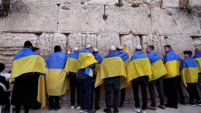 People wrap themselves with Ukraine national flag as they stand by the Western Wall